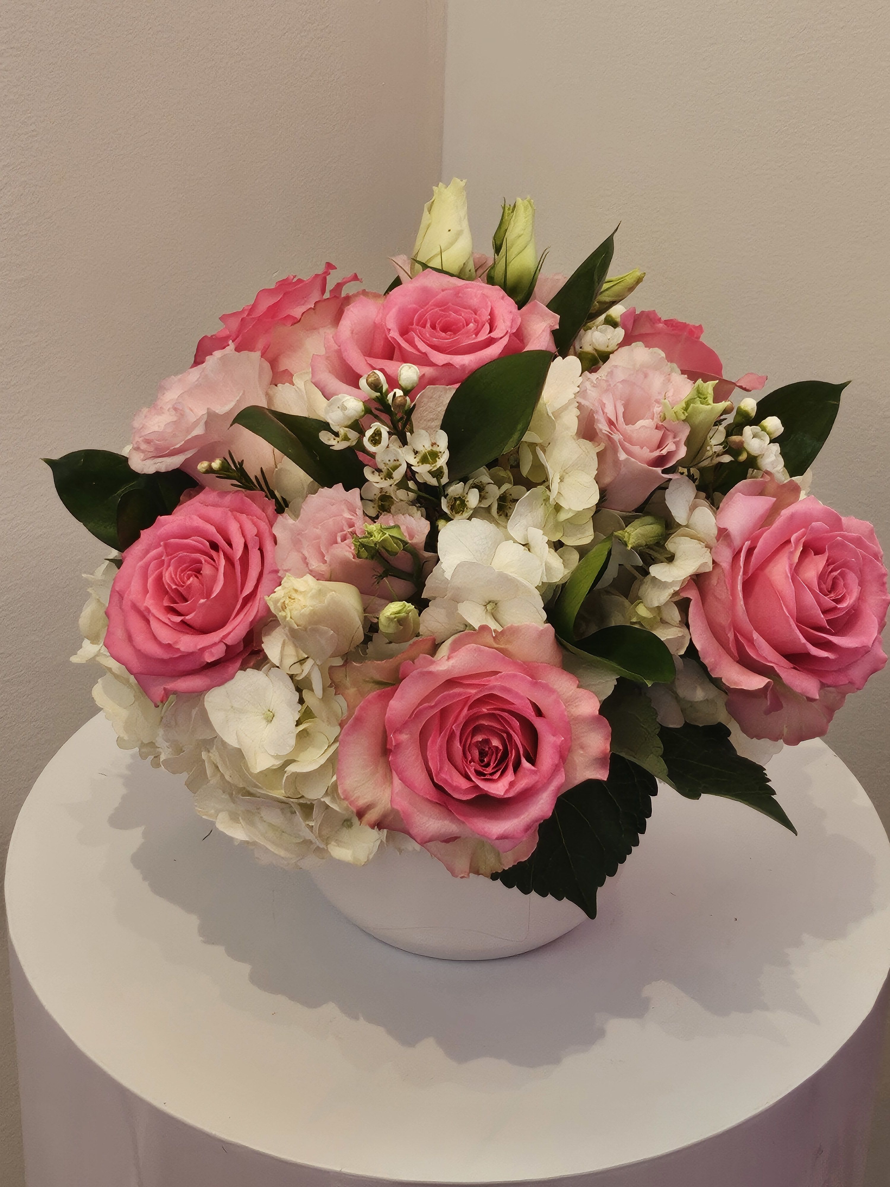 Pink roses and white hydrangeas arranged in a white bowl vase