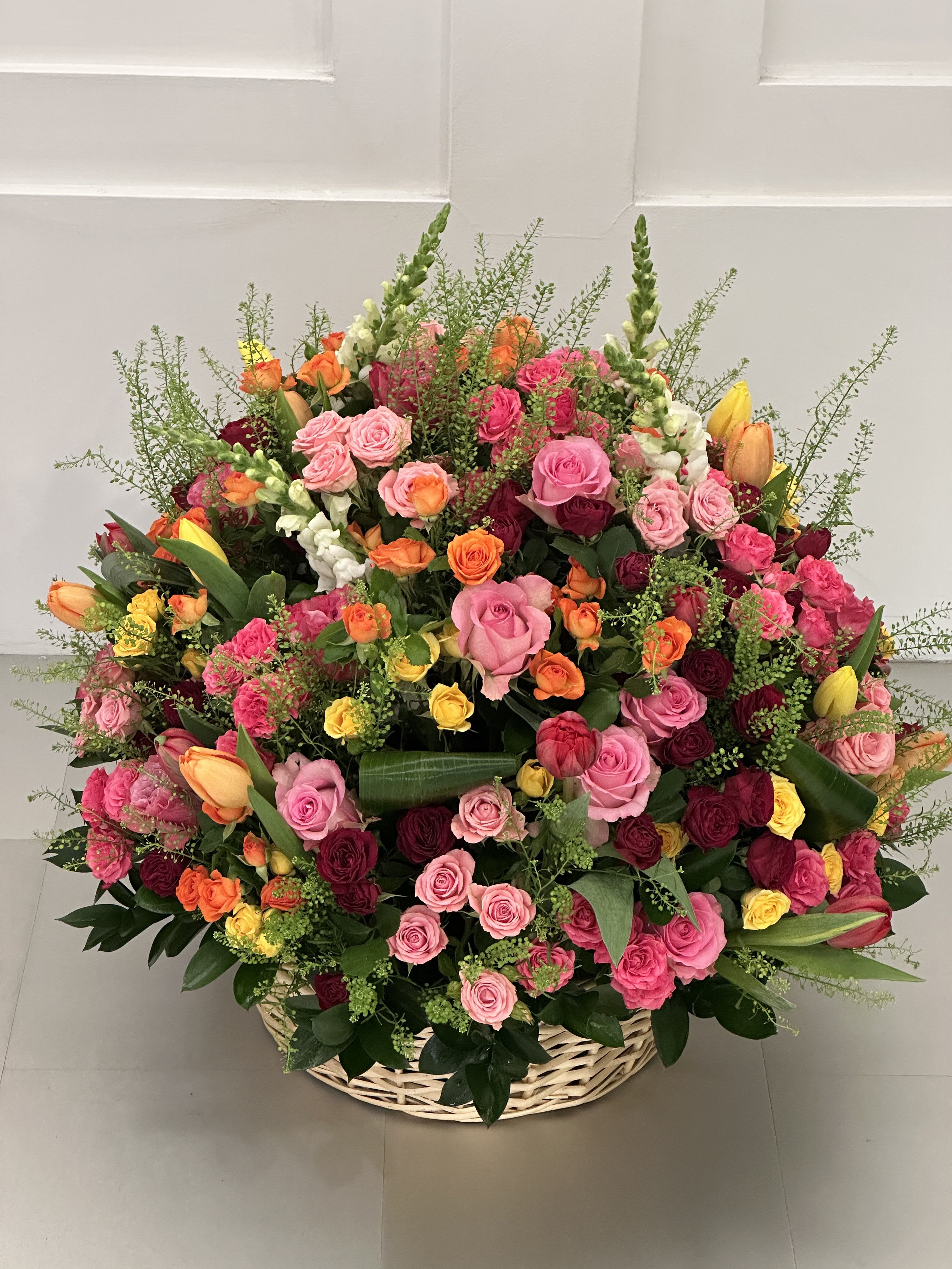 Large basket arrangement of pink, red, orange, and yellow roses
