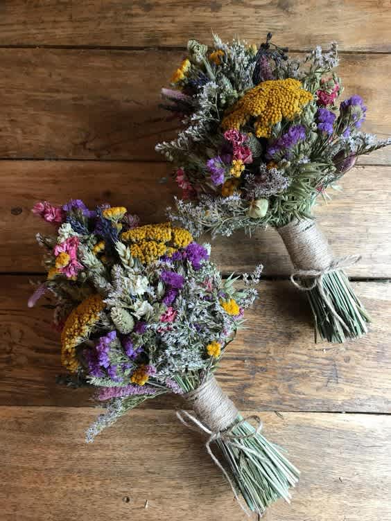 Two rustic hand-tied bouquets with purple, yellow, and pink dried flowers