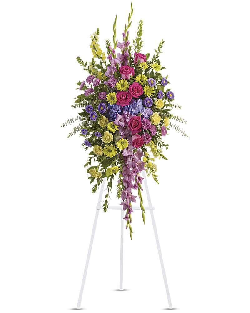 Tall standing floral spray with pink, purple, and yellow flowers on a white easel