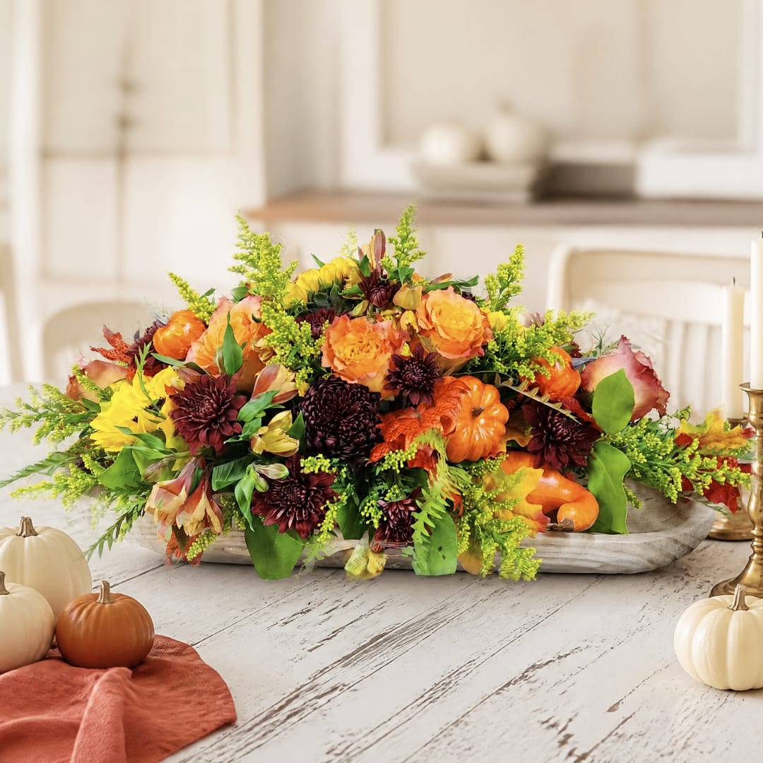Autumn floral centerpiece with orange and burgundy blooms in a low tray