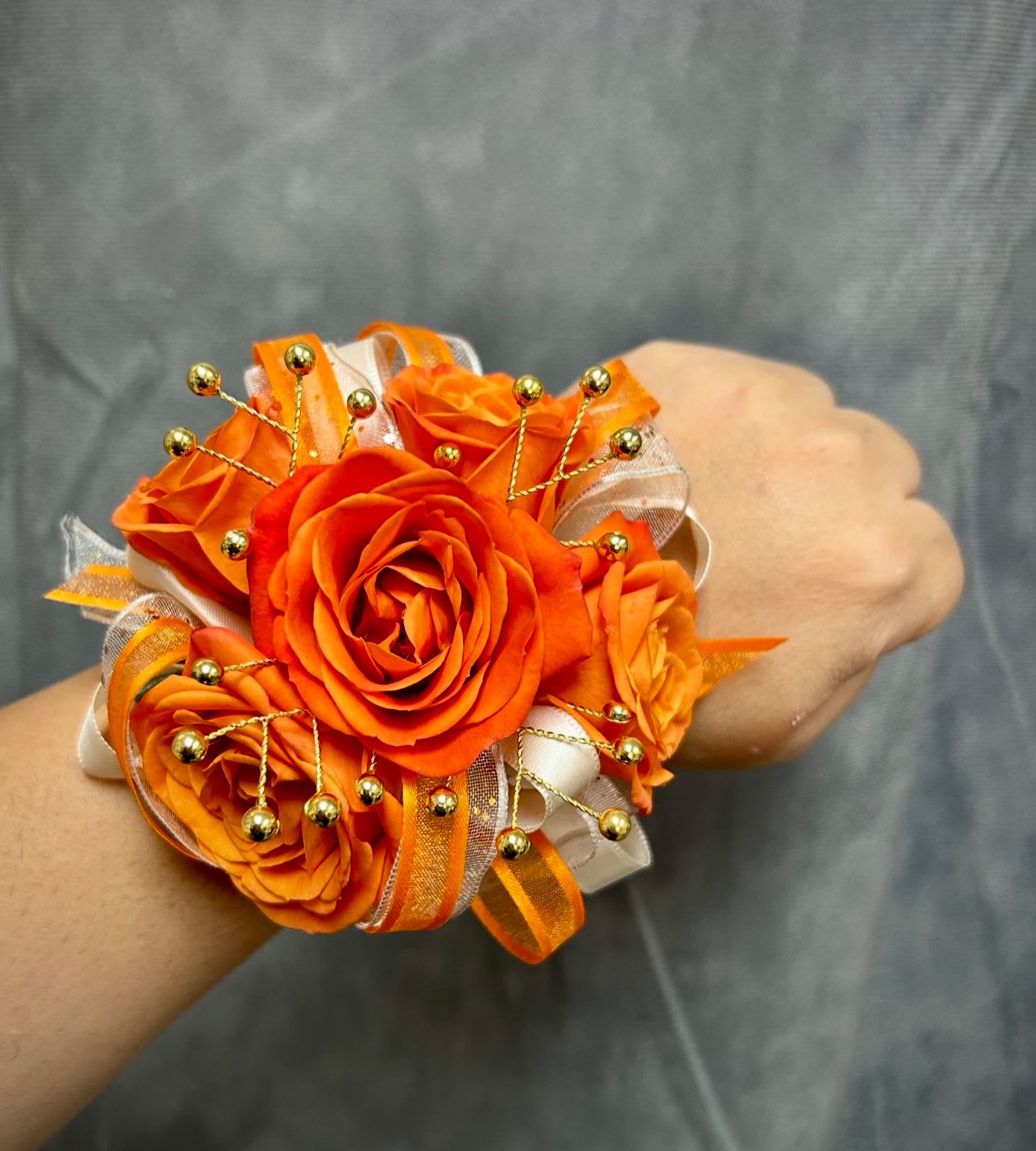 Orange rose wrist corsage with ribbon and gold bead accents
