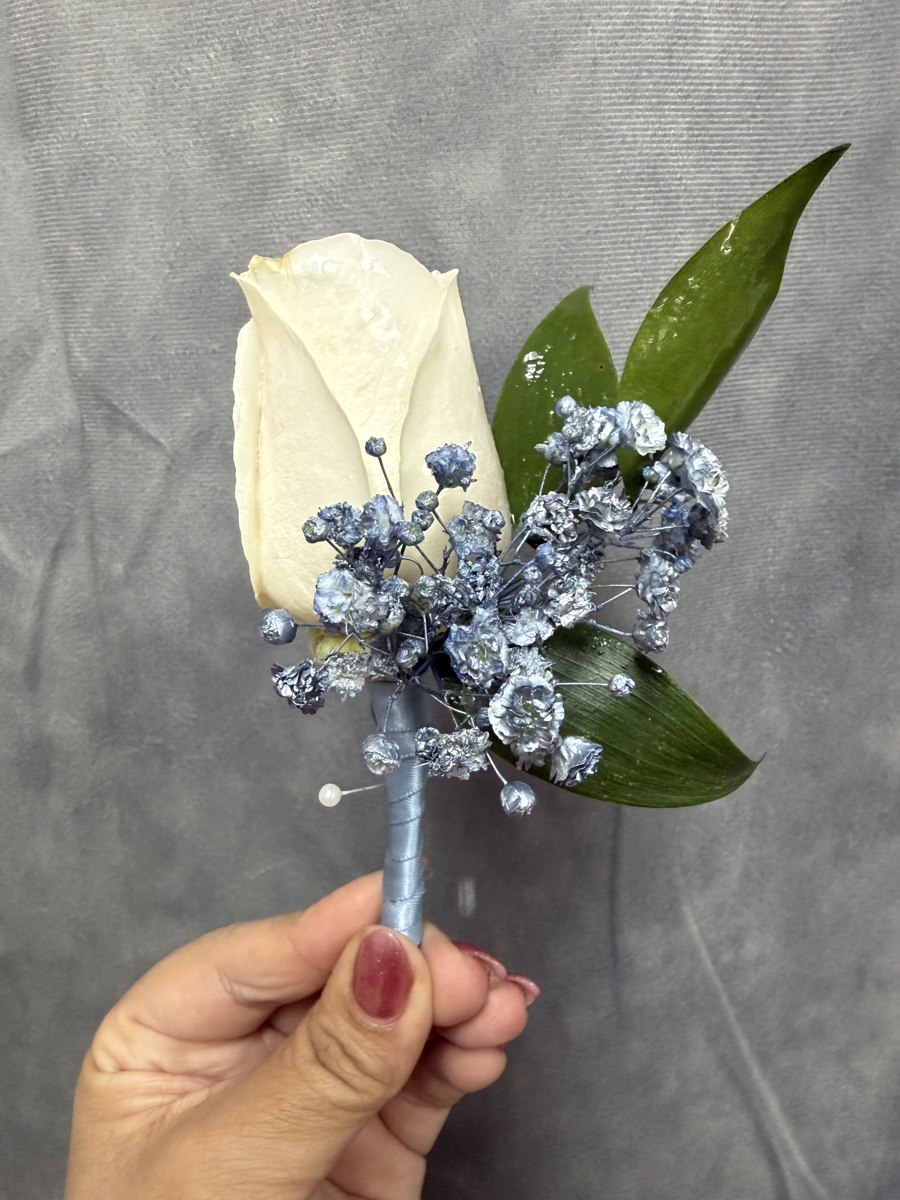 Dusty blue white boutonnière  - White rose boutonnière with Dusty-blue baby's breath and green leaves, wrapped with Dusty  blue ribbon for a refined, modern look-perfect for weddings or proms