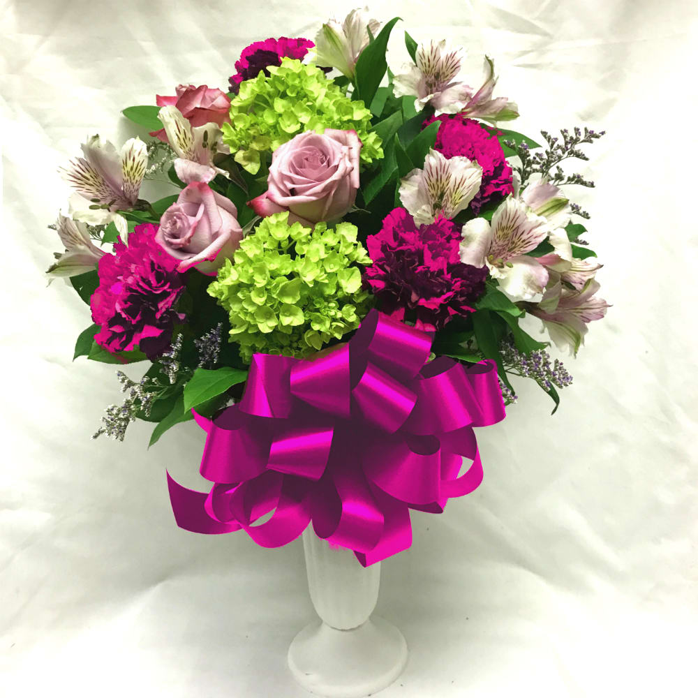 Bouquet of pink roses, green hydrangeas, and magenta carnations in a white vase