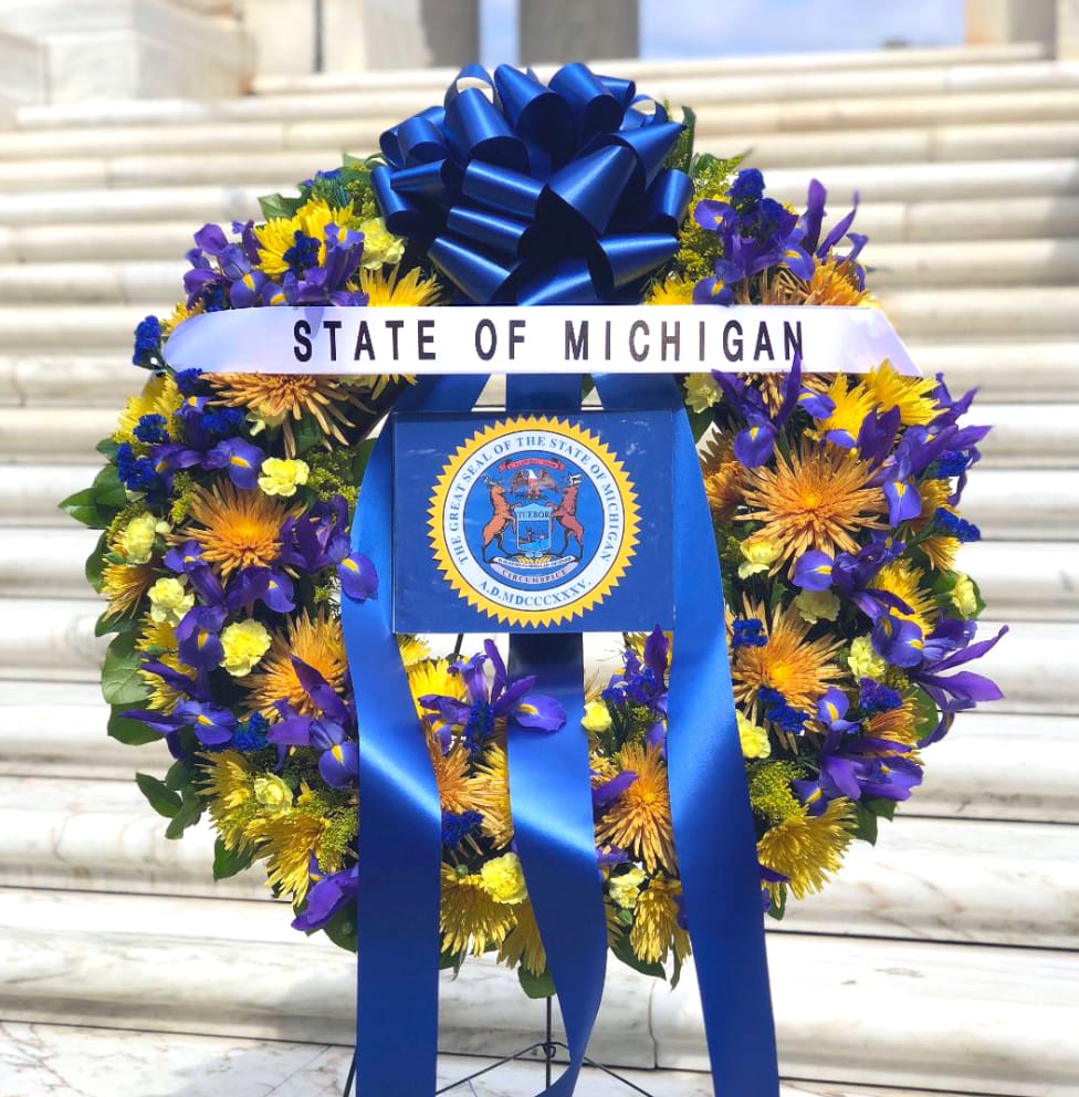 Blue and white memorial wreath with a ribbon and state seal