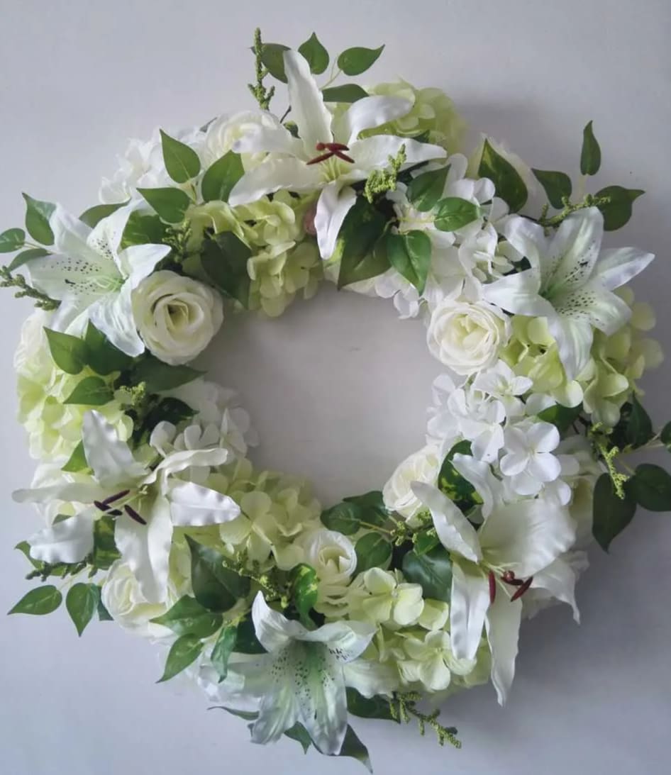 White floral wreath with lilies, roses, and hydrangeas