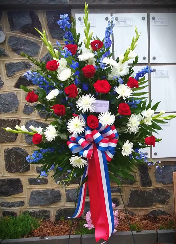 Standing floral spray with red roses, white daisies, and blue flowers