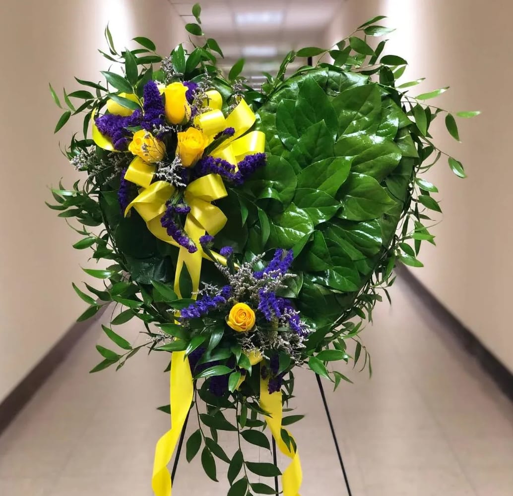 HEART OF GOLD [TT-ANC92] - The Heart of Gold standing spray by Twin Towers Florist  A foliage-covered heart arrives mounted on an easel, decorated with clusters of yellow roses and statice with satin ribbon.. Each leaf is hand pinned to the heart form in a scale effect, and wet floral foam in a small cage keeps the flowers hydrated.. The Heart of Gold standing heart spray on easel is memorable and heartfelt expression.of love.  Approximately 19" W x 22" H      As Shown : TT-ANC92  
