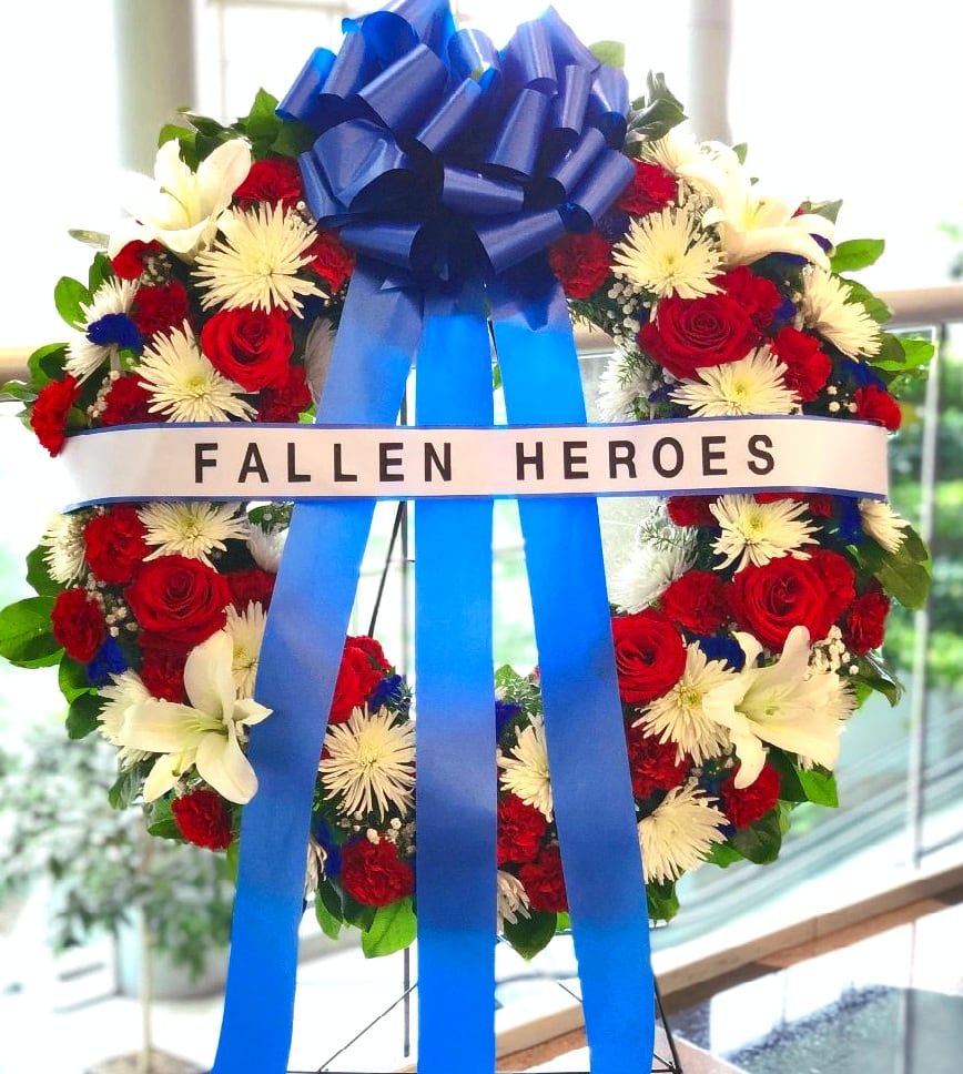 Red and white floral wreath with a blue ribbon and "FALLEN HEROES" banner