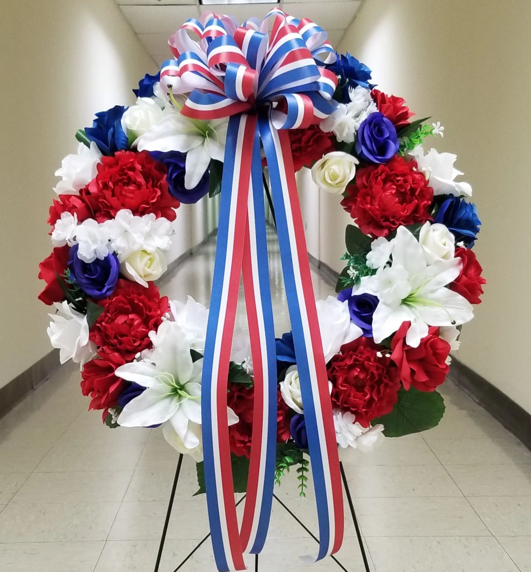 Red, white, and blue floral wreath with a striped ribbon bow
