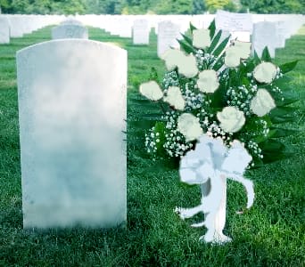 White floral spray beside a gravestone in a cemetery