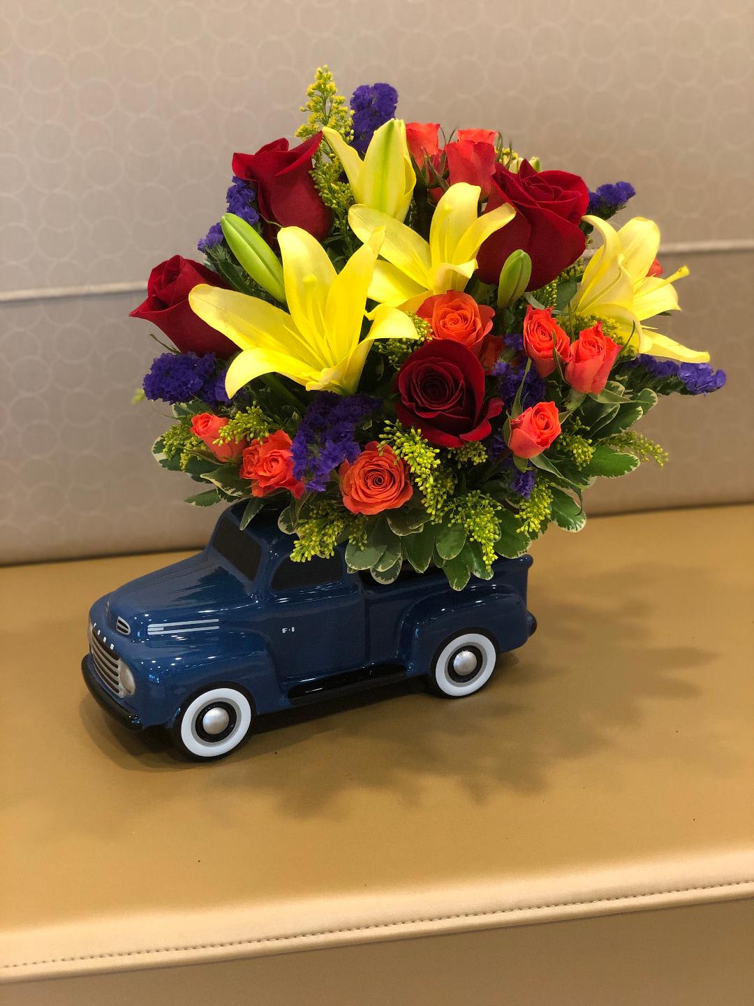 Bouquet of red roses and yellow lilies in a blue toy truck