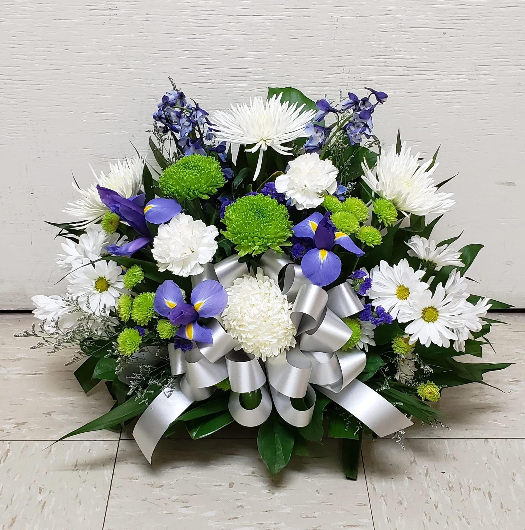 White and purple floral arrangement with a silver ribbon bow