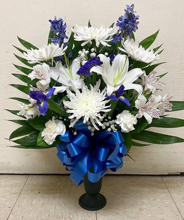 White lilies and chrysanthemums with blue flowers in a vase, tied with a blue ribbon