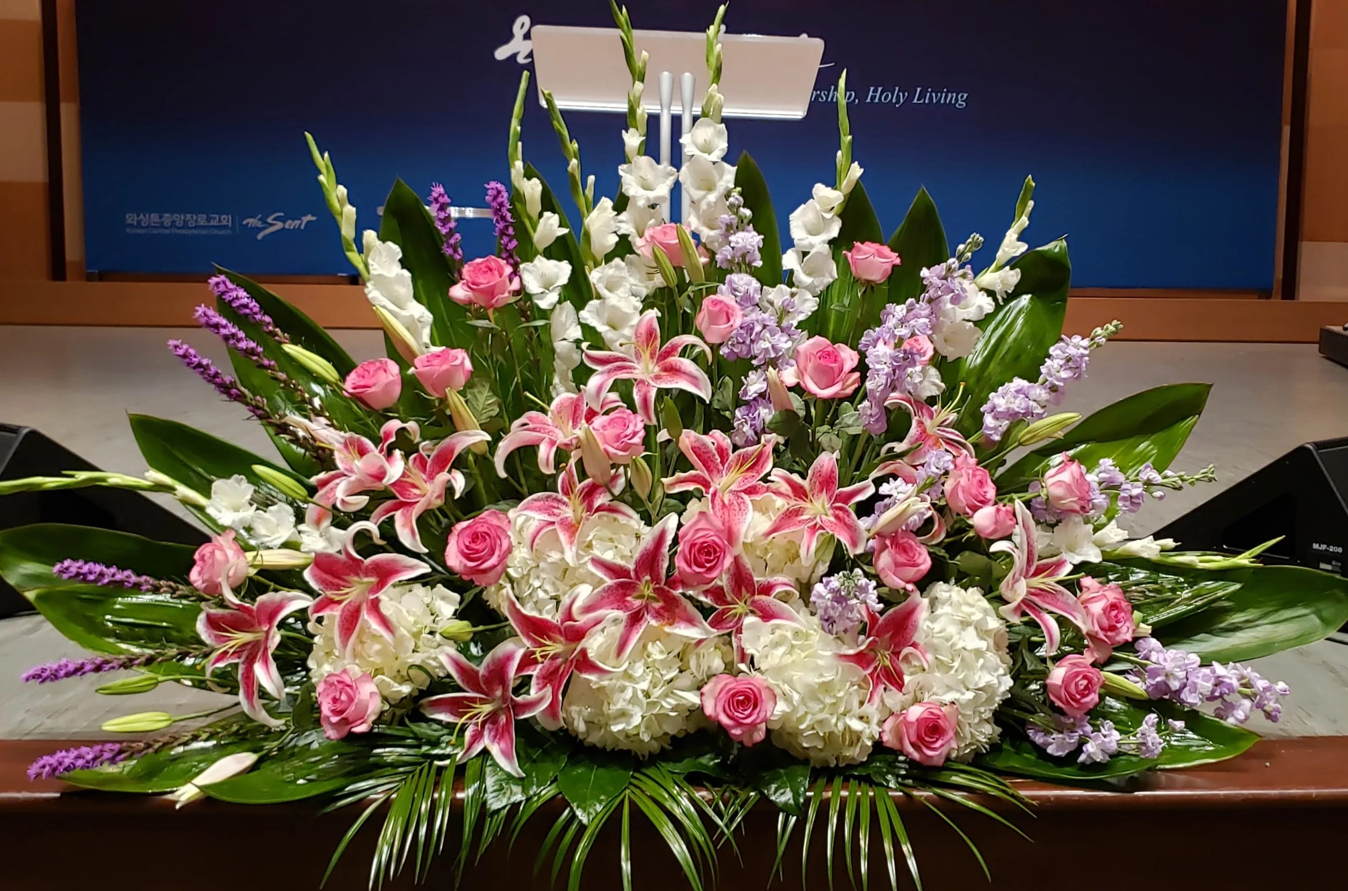 Large pink and white lily and rose arrangement with hydrangeas and lavender flowers in a low spray design
