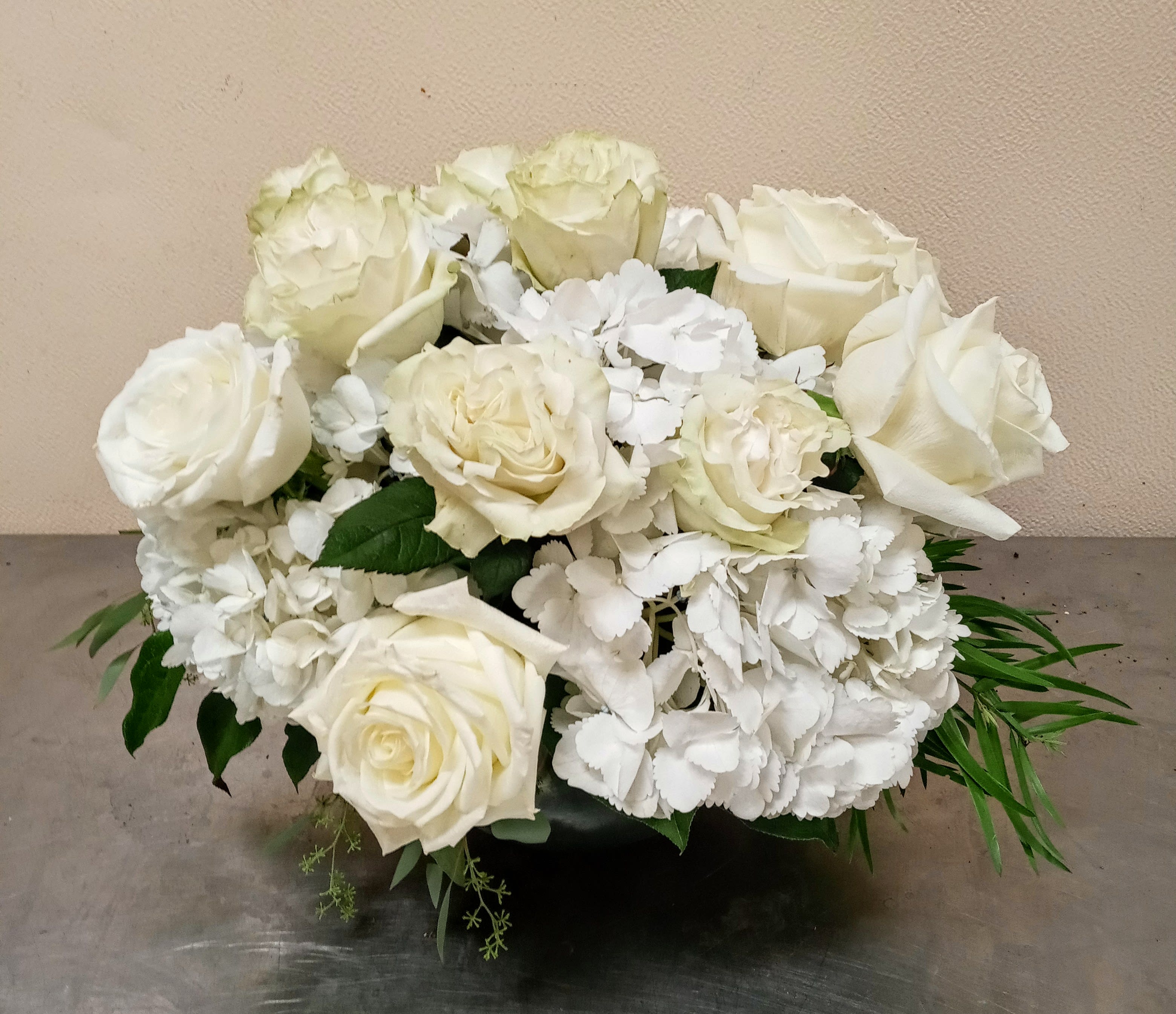 White roses and hydrangeas arranged in a low black container