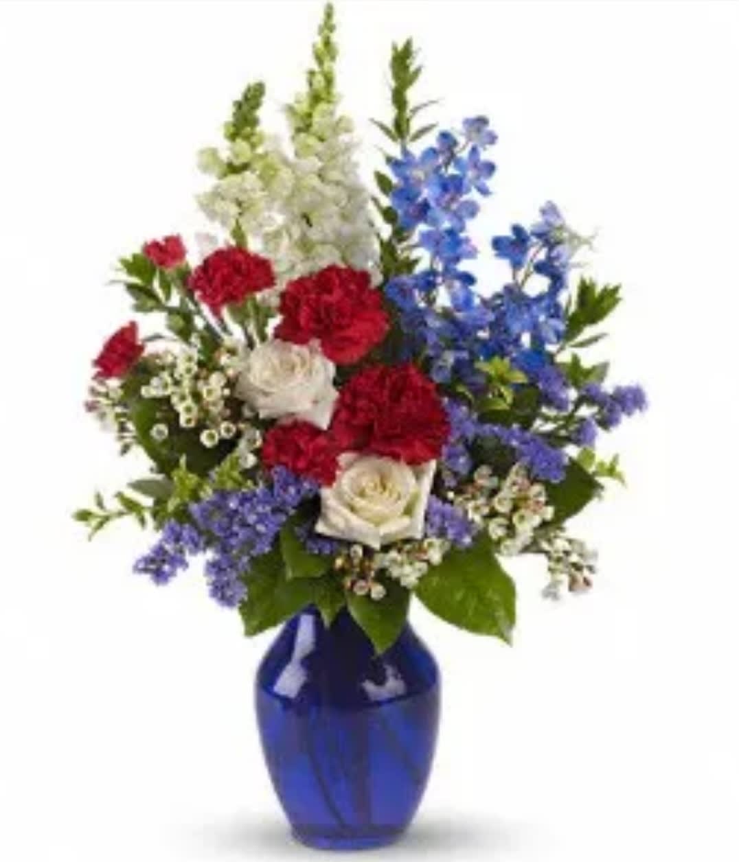 Red, white, and blue flowers arranged in a cobalt vase