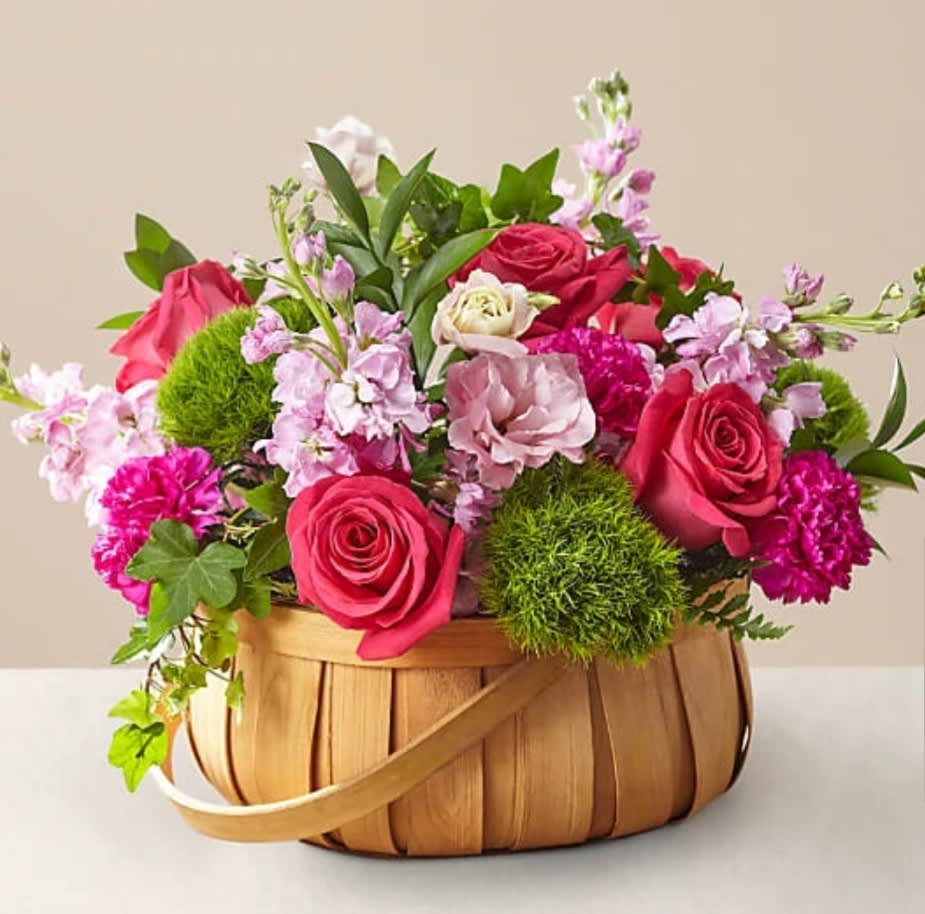 Basket arrangement of pink roses and mixed blooms