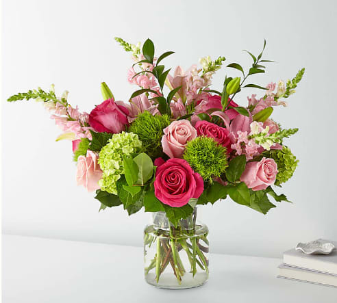 Pink roses and lilies arranged in a clear glass vase