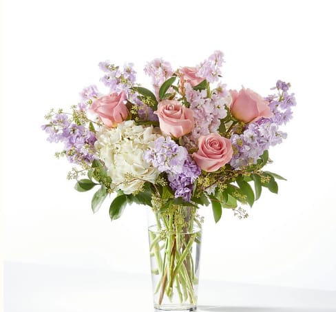 Pink roses and lavender flowers in a clear glass vase