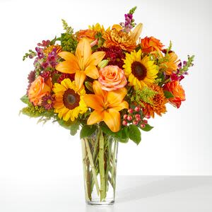 Bouquet of orange and yellow flowers in a clear glass vase