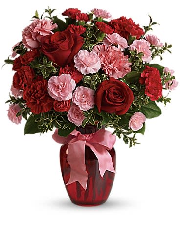 Red roses and pink carnations in a red vase with a pink ribbon