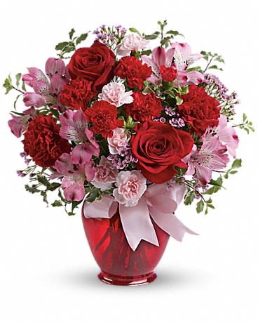 Red roses and pink carnations in a red vase with a pink ribbon