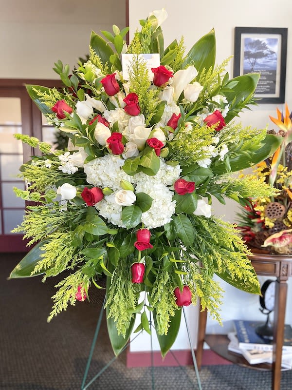 Tall standing spray of red and white roses with white hydrangeas on a green easel