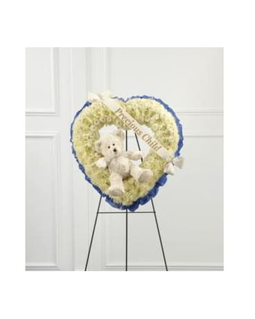 Heart-shaped white floral wreath with a teddy bear and ribbon on an easel