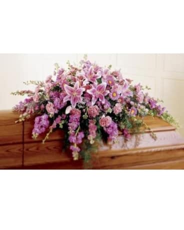 Pink and lavender floral casket spray on a wooden casket