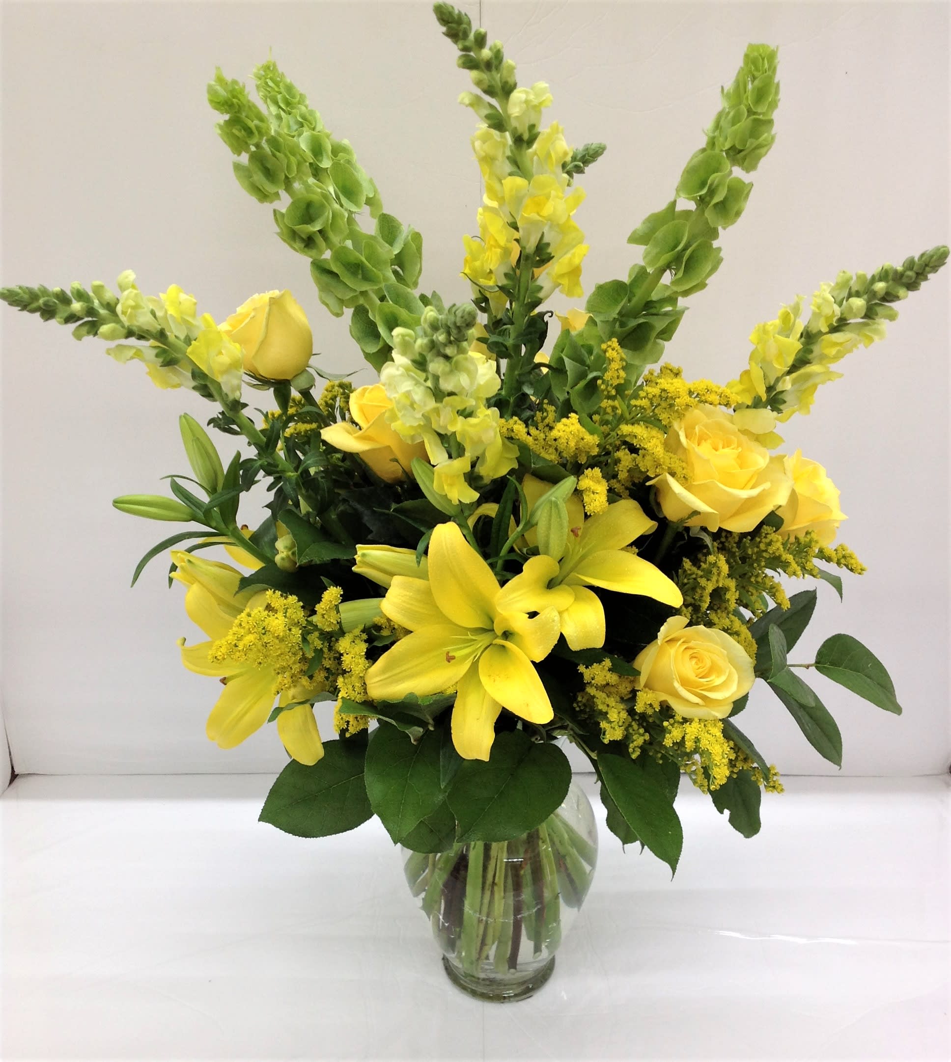 Yellow roses and lilies in a clear glass vase