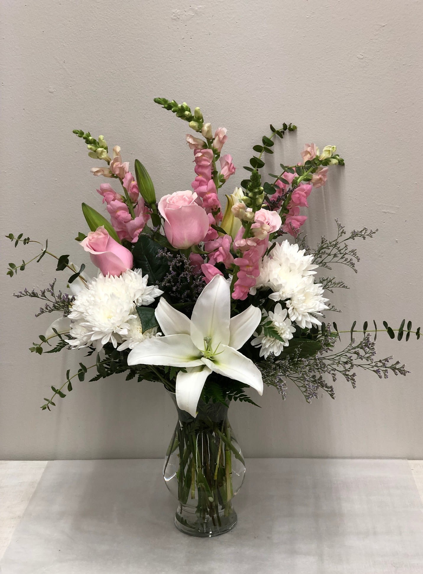 Pink roses, white lilies, and white chrysanthemums in a glass vase