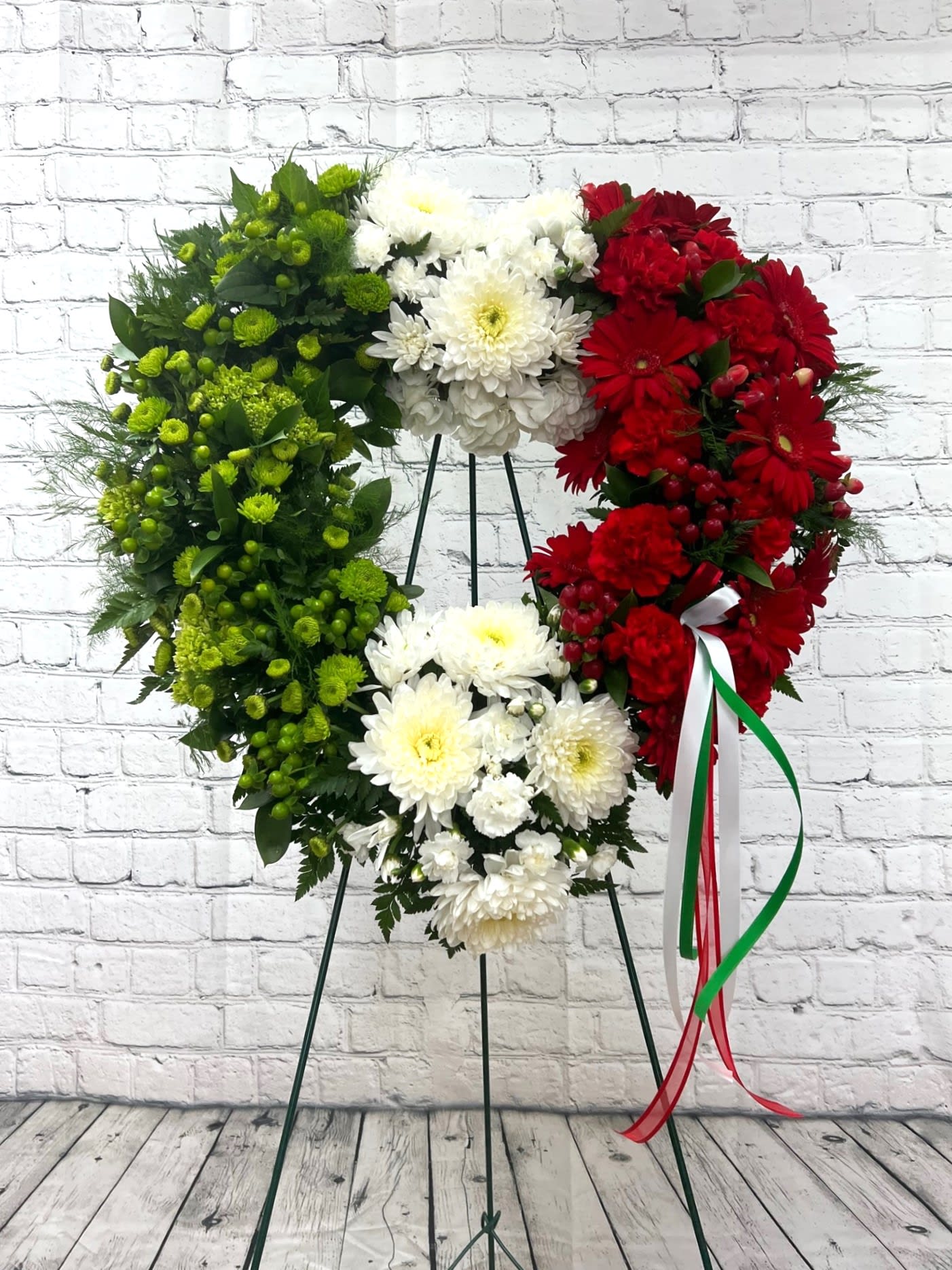 Heart-shaped floral wreath in red, white, and green on a stand