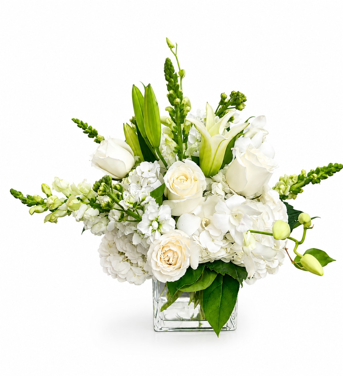 White floral arrangement in a clear square vase with lilies, roses, and hydrangeas