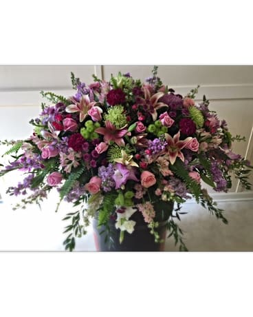 Large mixed bouquet of pink, purple, and green flowers in a dark vase