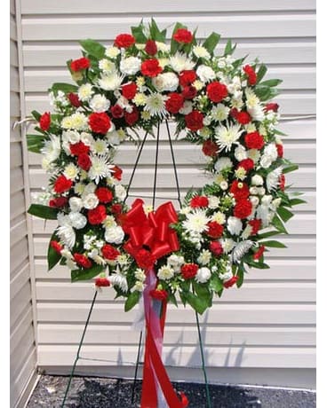 Large red and white floral wreath on a stand with a red bow