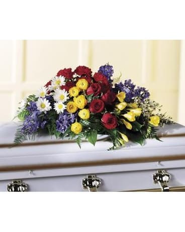 Colorful floral casket spray with roses, daisies, and yellow blooms