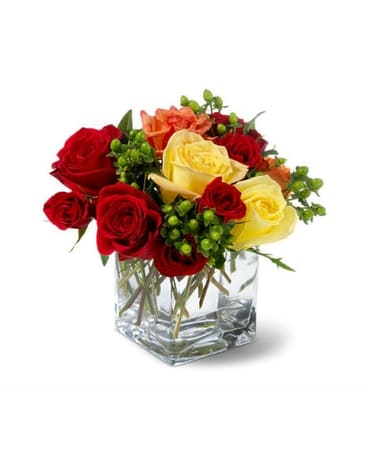 Bouquet of red, yellow, and orange roses in a clear square vase