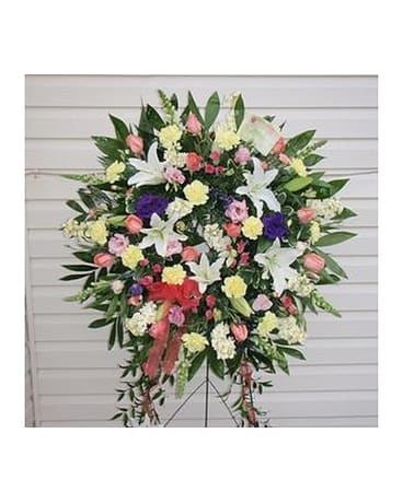 Standing floral spray with lilies, roses, and carnations in pink, white, yellow, and purple