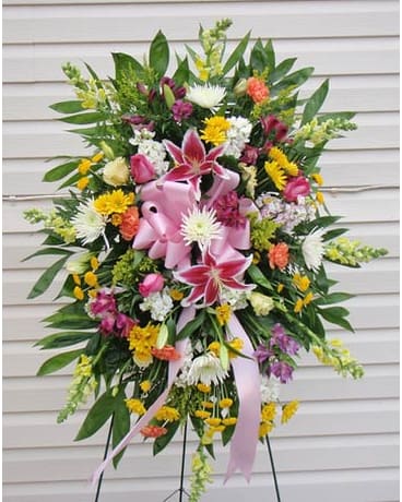 Standing floral spray with pink lilies and mixed blooms on a ribboned easel