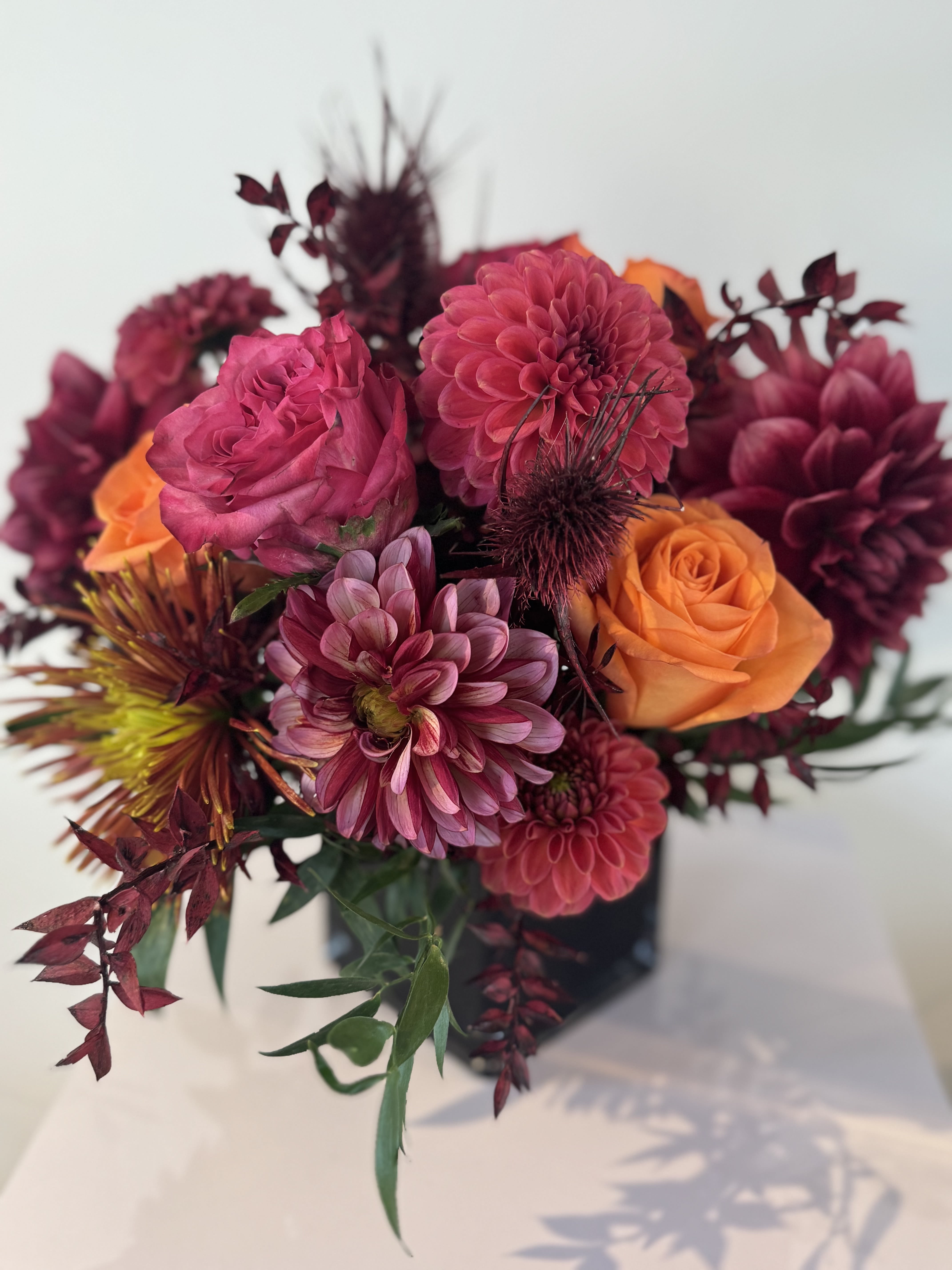 Bouquet of pink and orange flowers in a dark vase