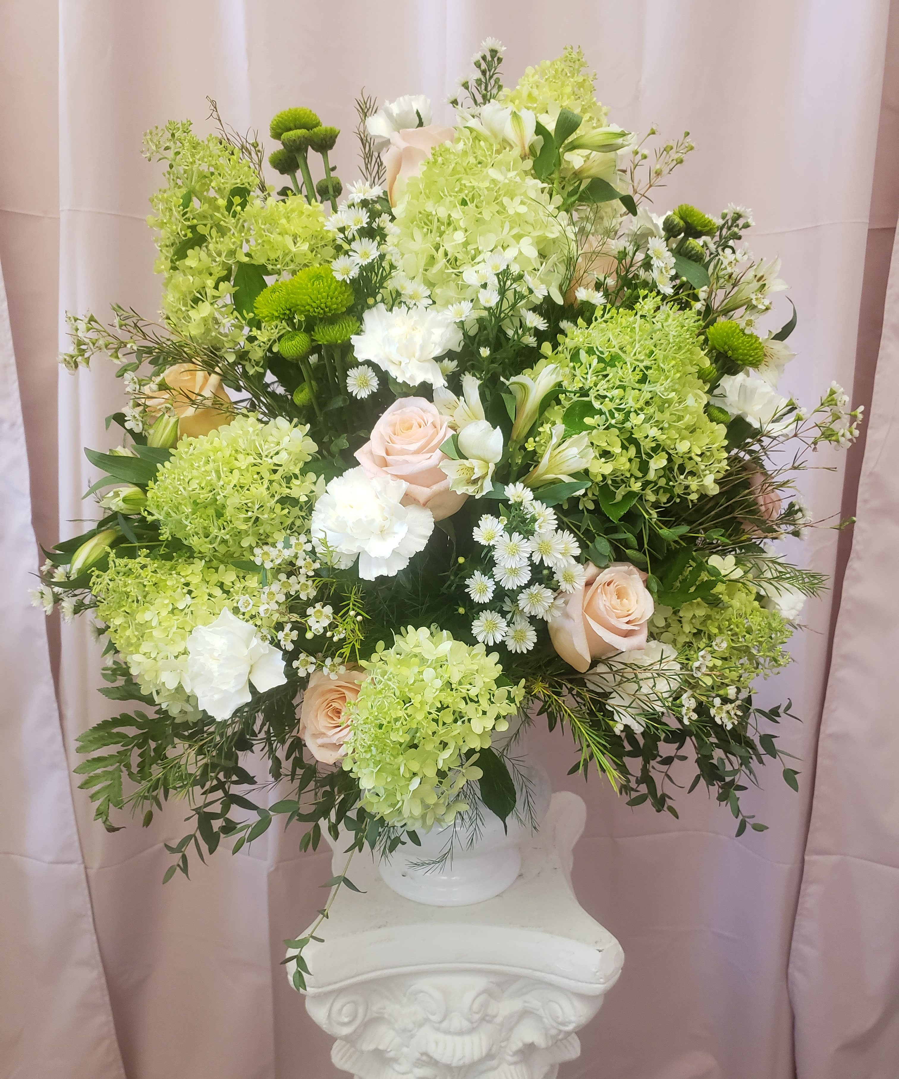 Large bouquet of pale roses, white blooms, and green flowers in a white vase