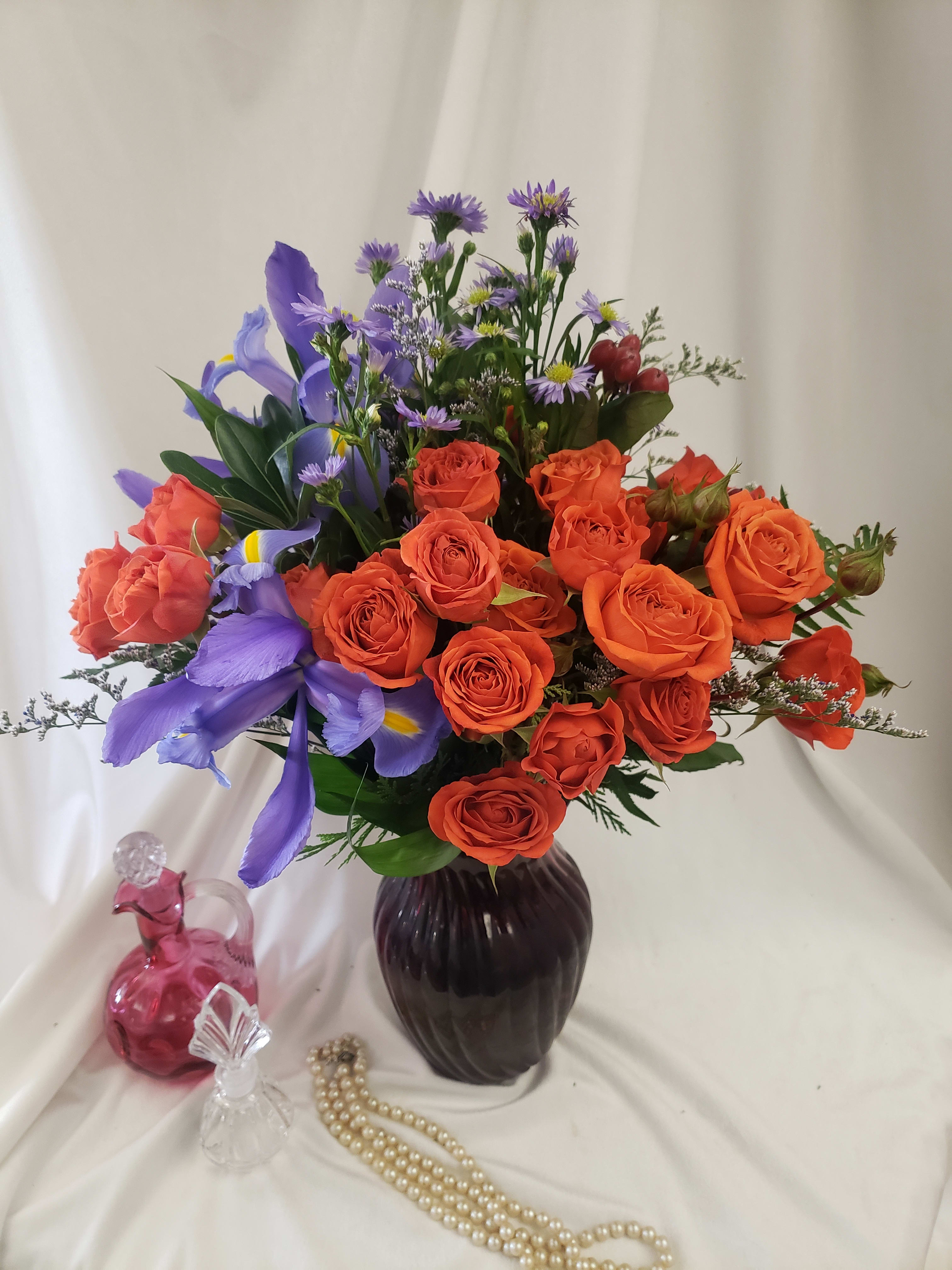 Orange roses and purple irises in a dark vase