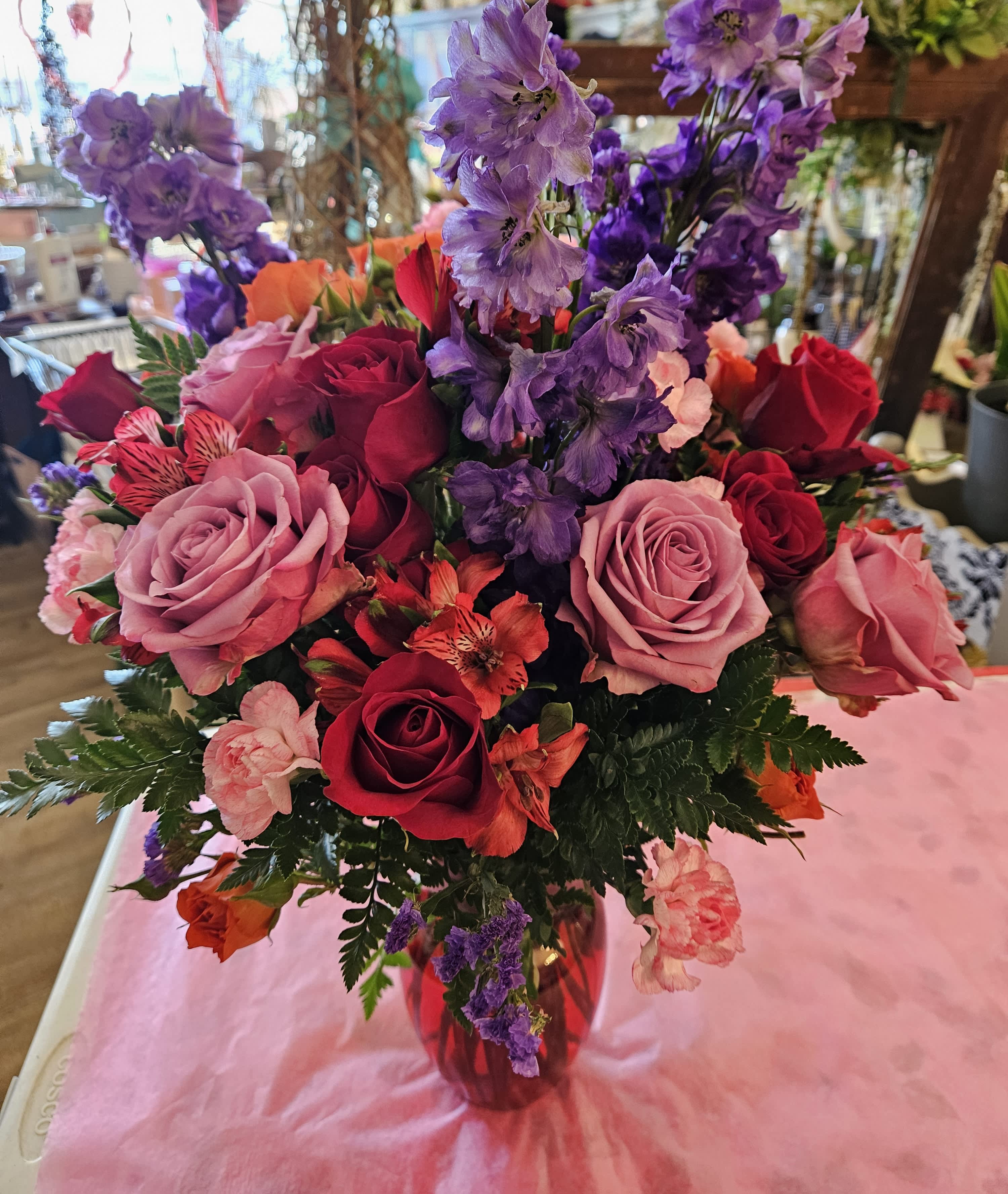 Mixed bouquet of roses and purple flowers in a glass vase