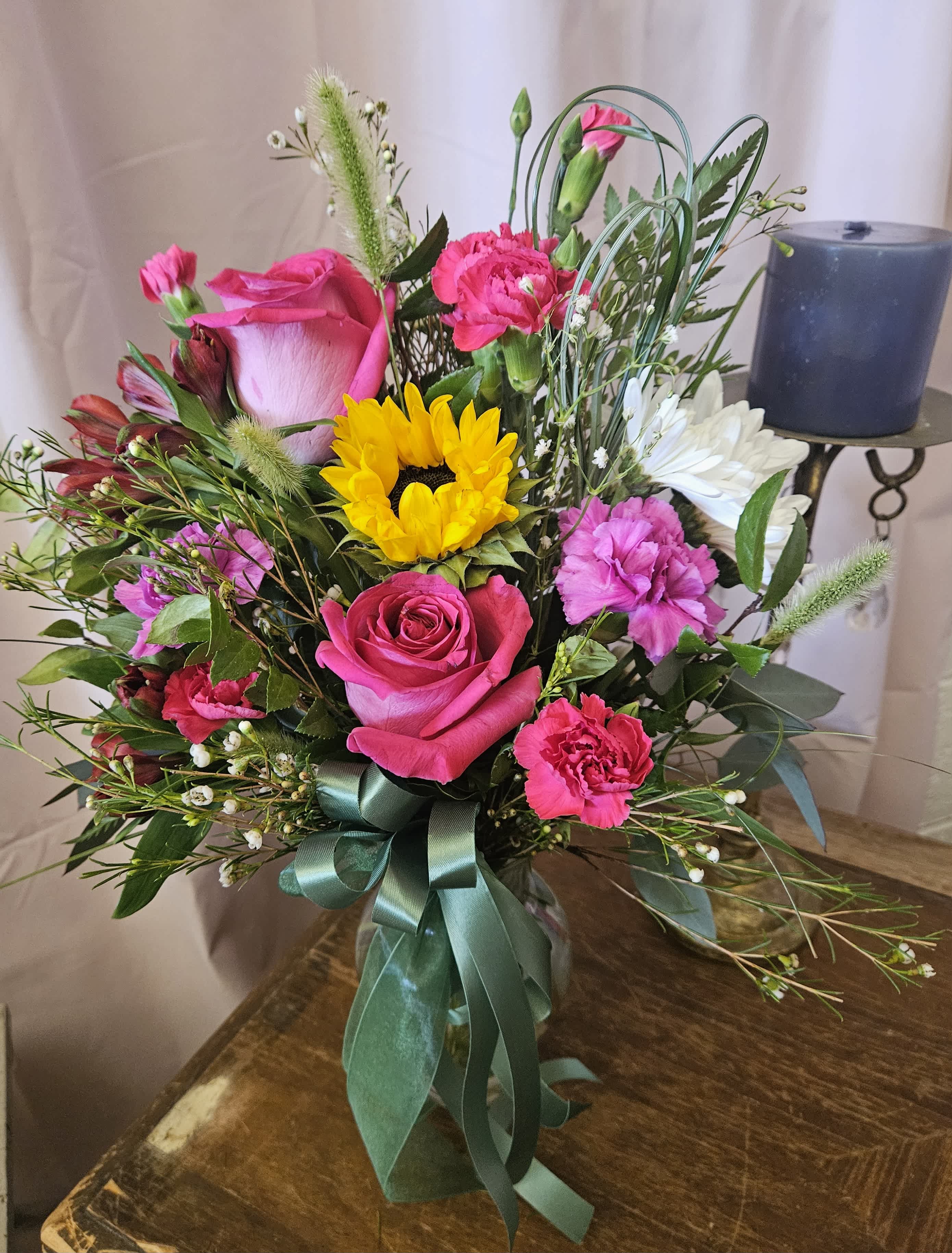 Bouquet of pink roses, carnations, and a sunflower with a ribbon tie