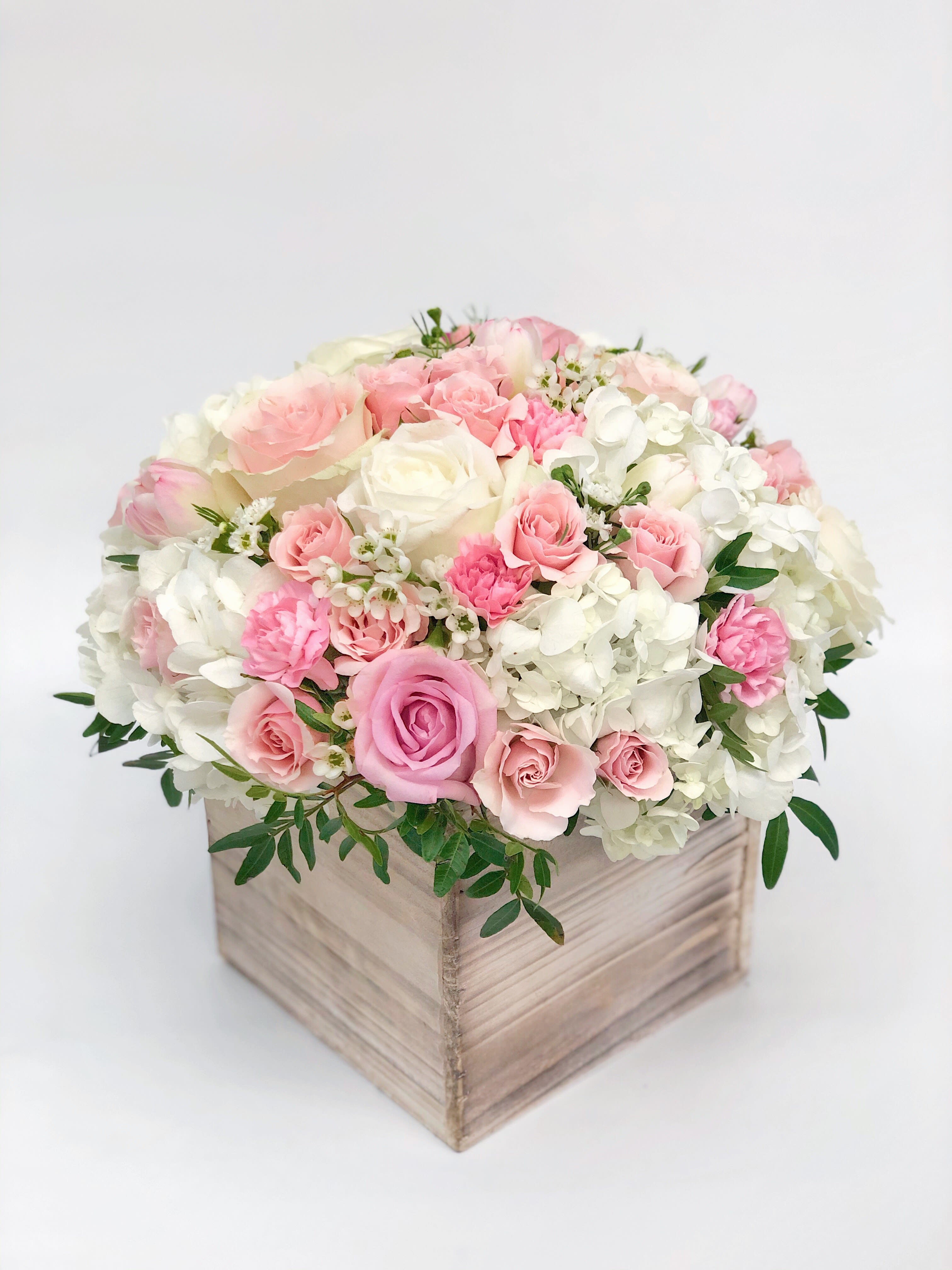 Pink and white roses arranged in a wooden box