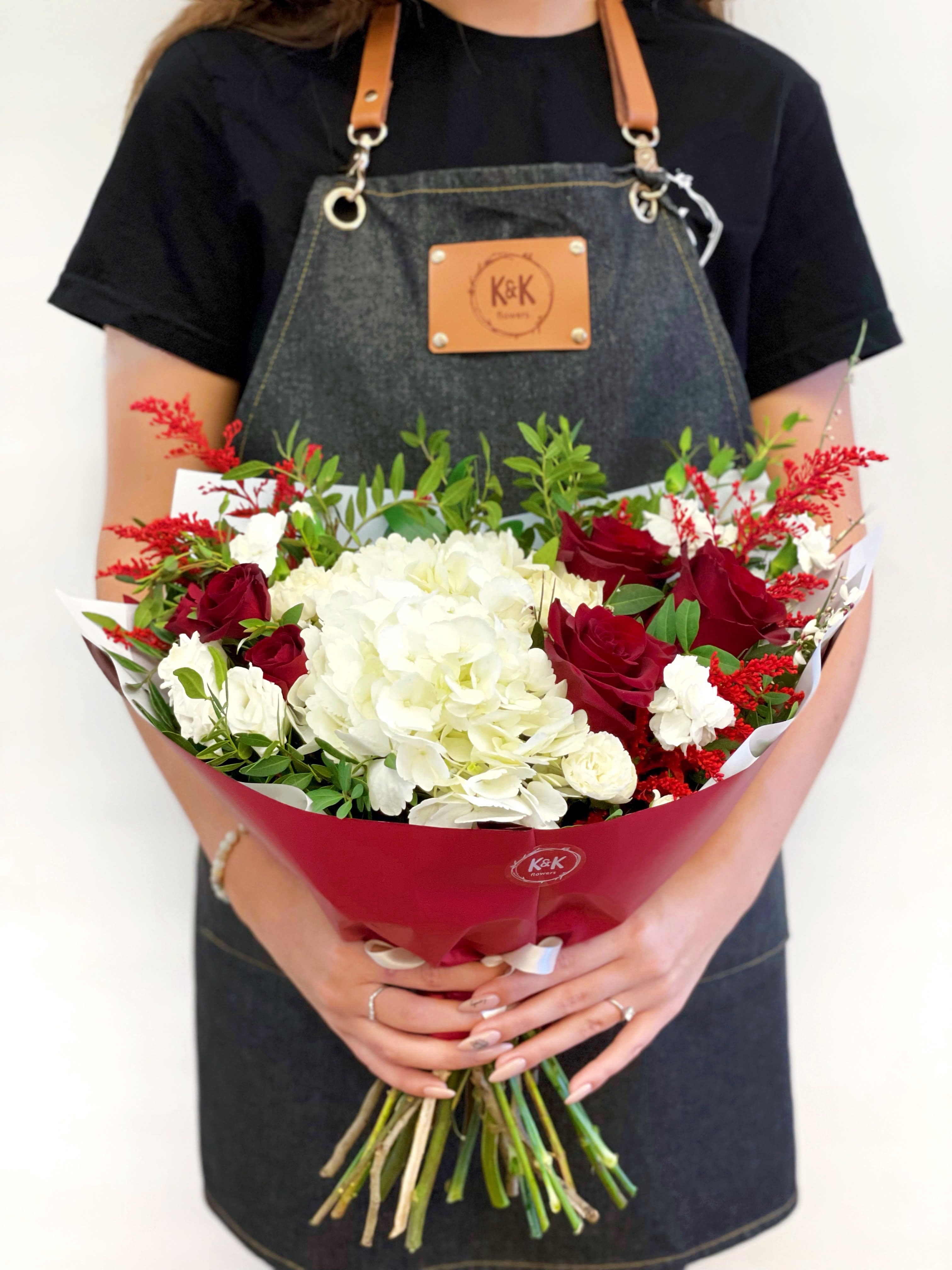 Bouquet of red roses and white hydrangeas wrapped in red paper