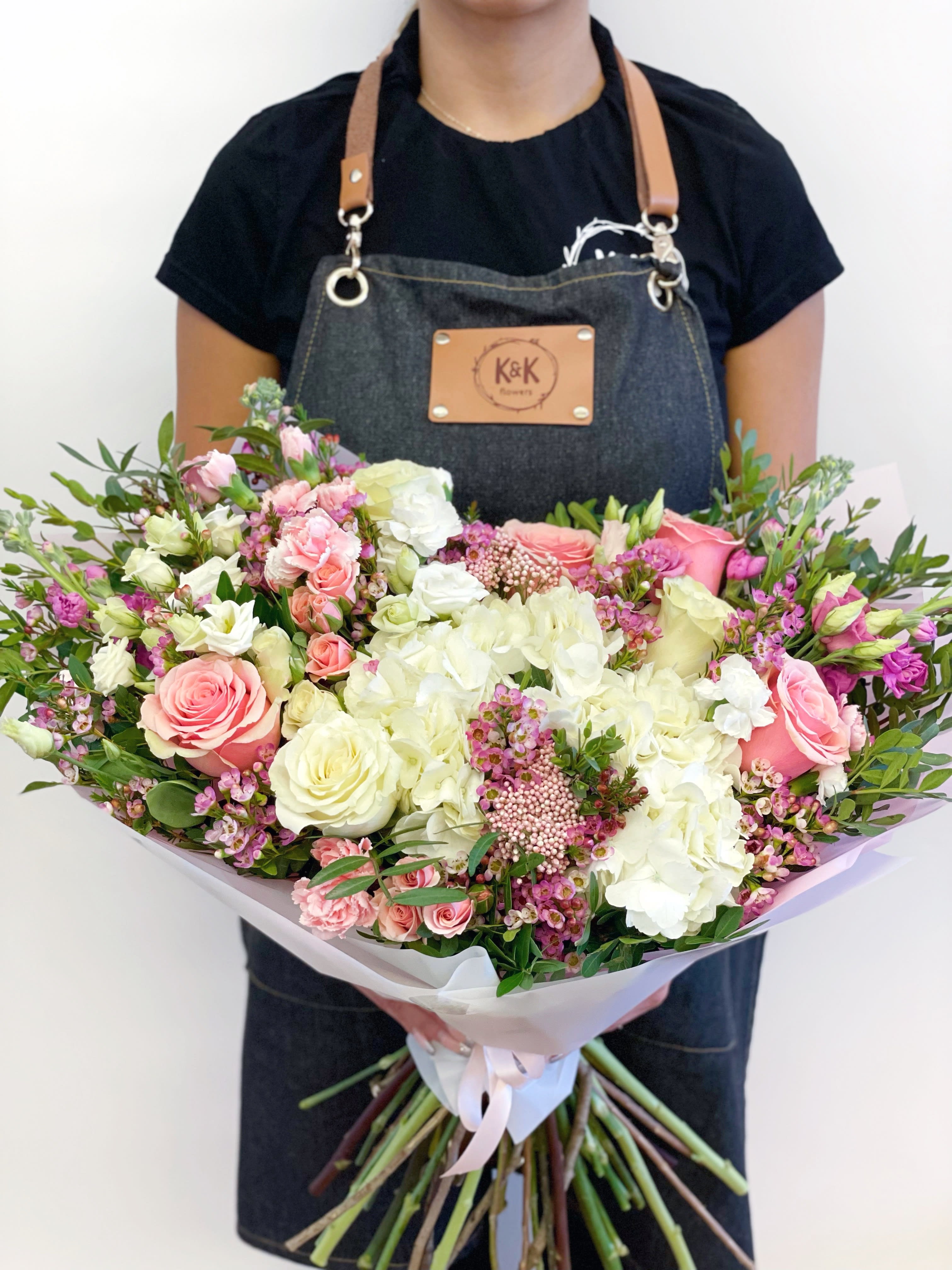Large bouquet of pink and white roses with hydrangeas held by a florist