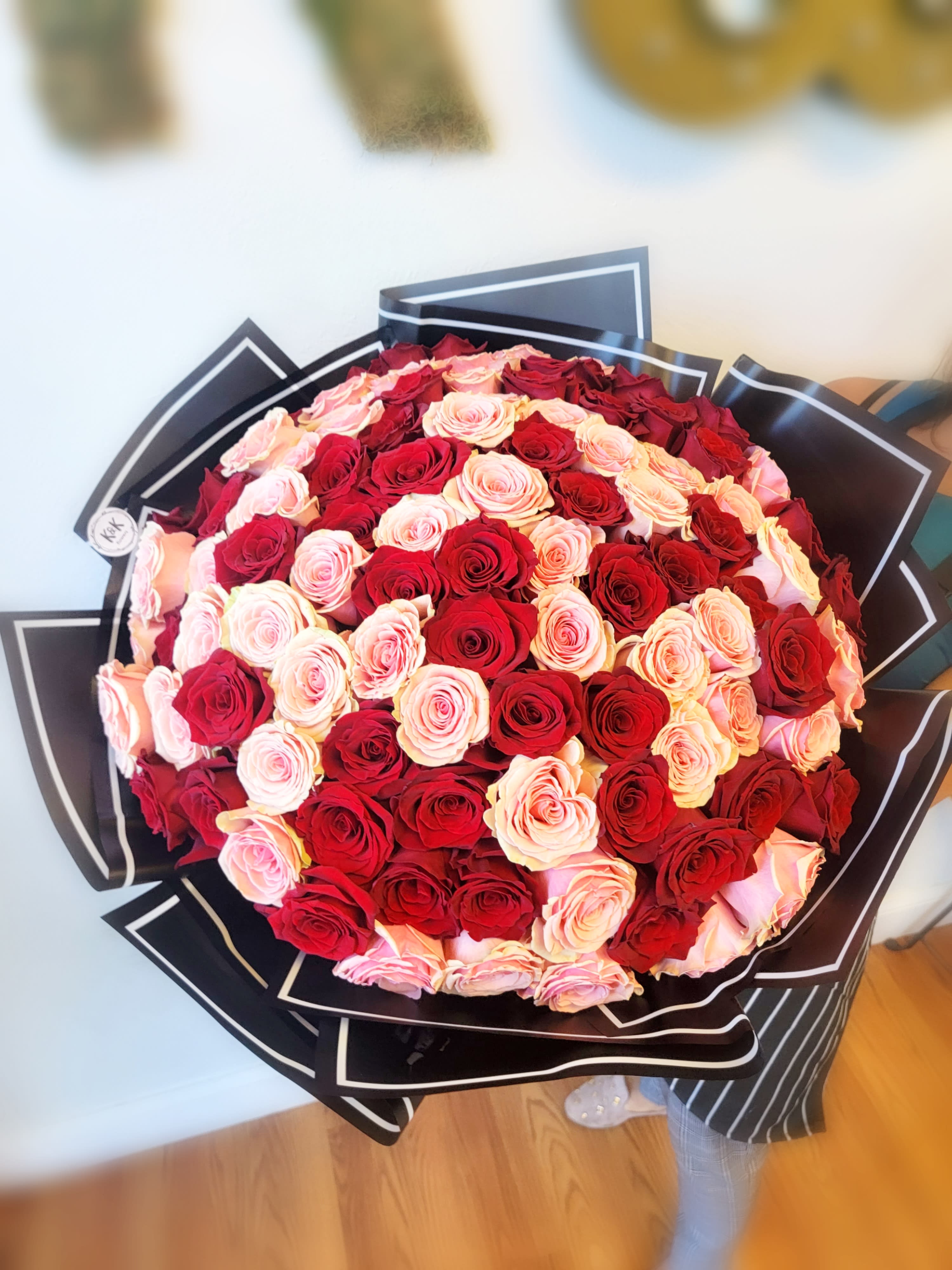 Large bouquet of red and blush pink roses wrapped in black paper