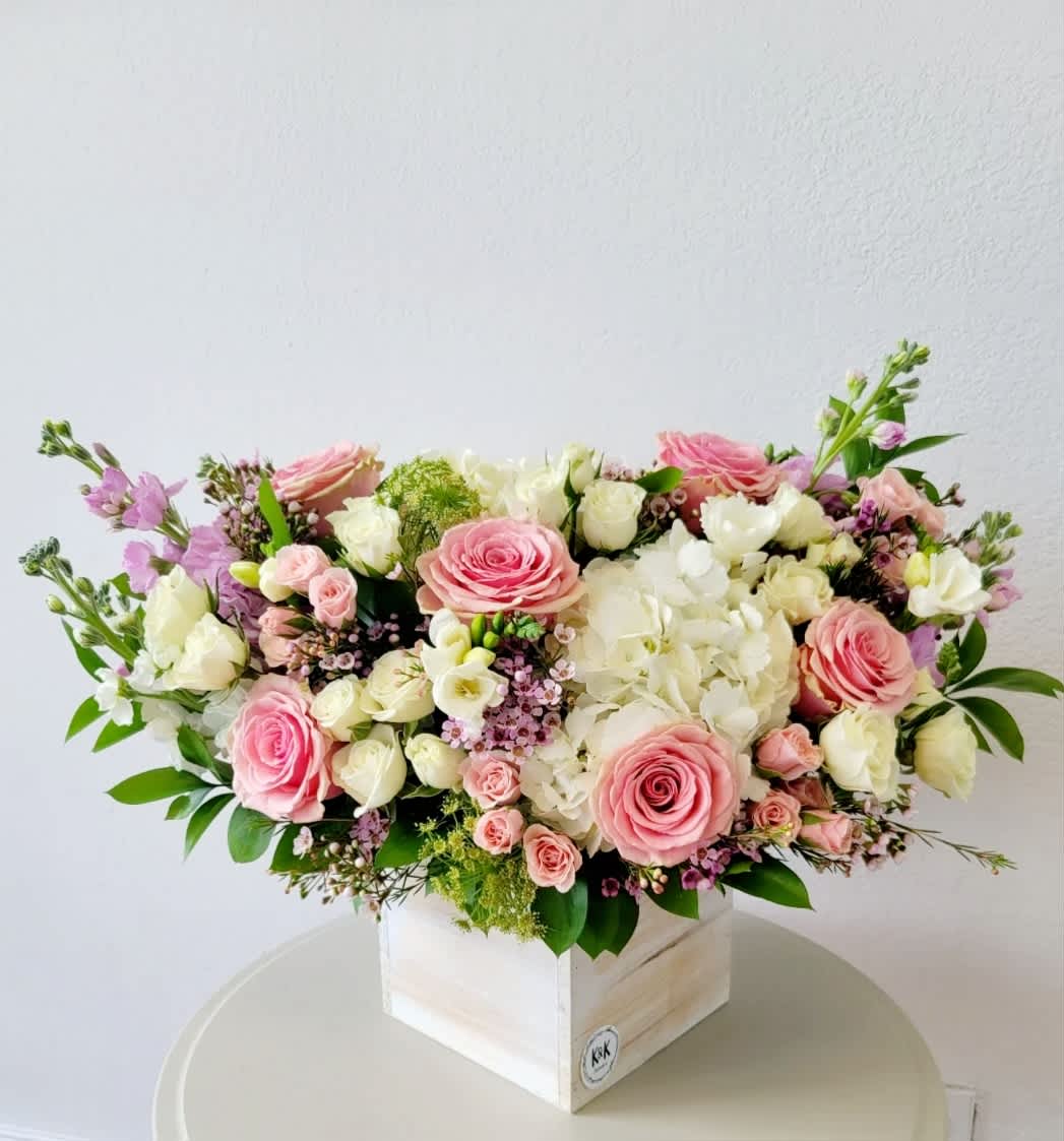 Pink and white rose arrangement in a white wooden box